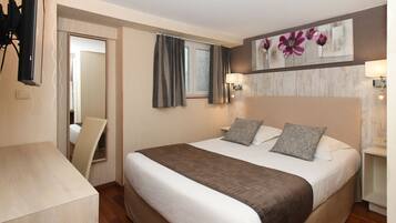 Habitación de hotel impecable con una cama grande, lámparas de noche, un cuadro en la pared y un escritorio con silla.