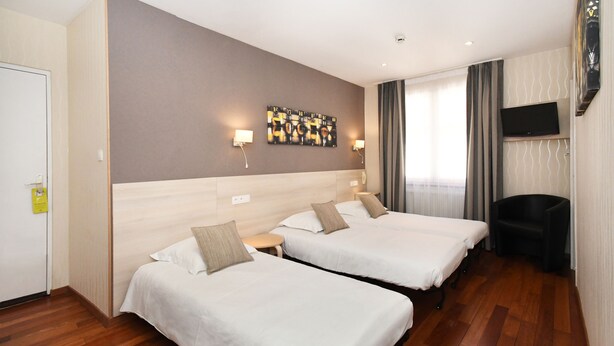 A hotel room with two beds, a flat-screen TV mounted on the wall, a small round table, and a chair. - Hôtel du Centre (Molsheim)