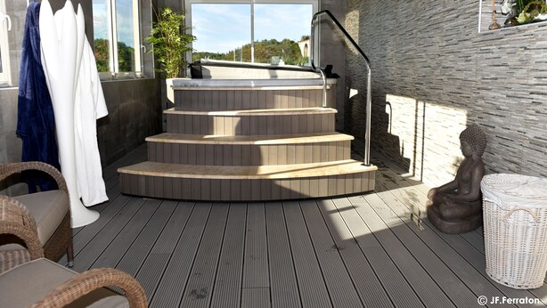 A spa area with a wooden deck, a hot tub, and a statue. - Hôtel Beau Site (Val-d'Arcomie)