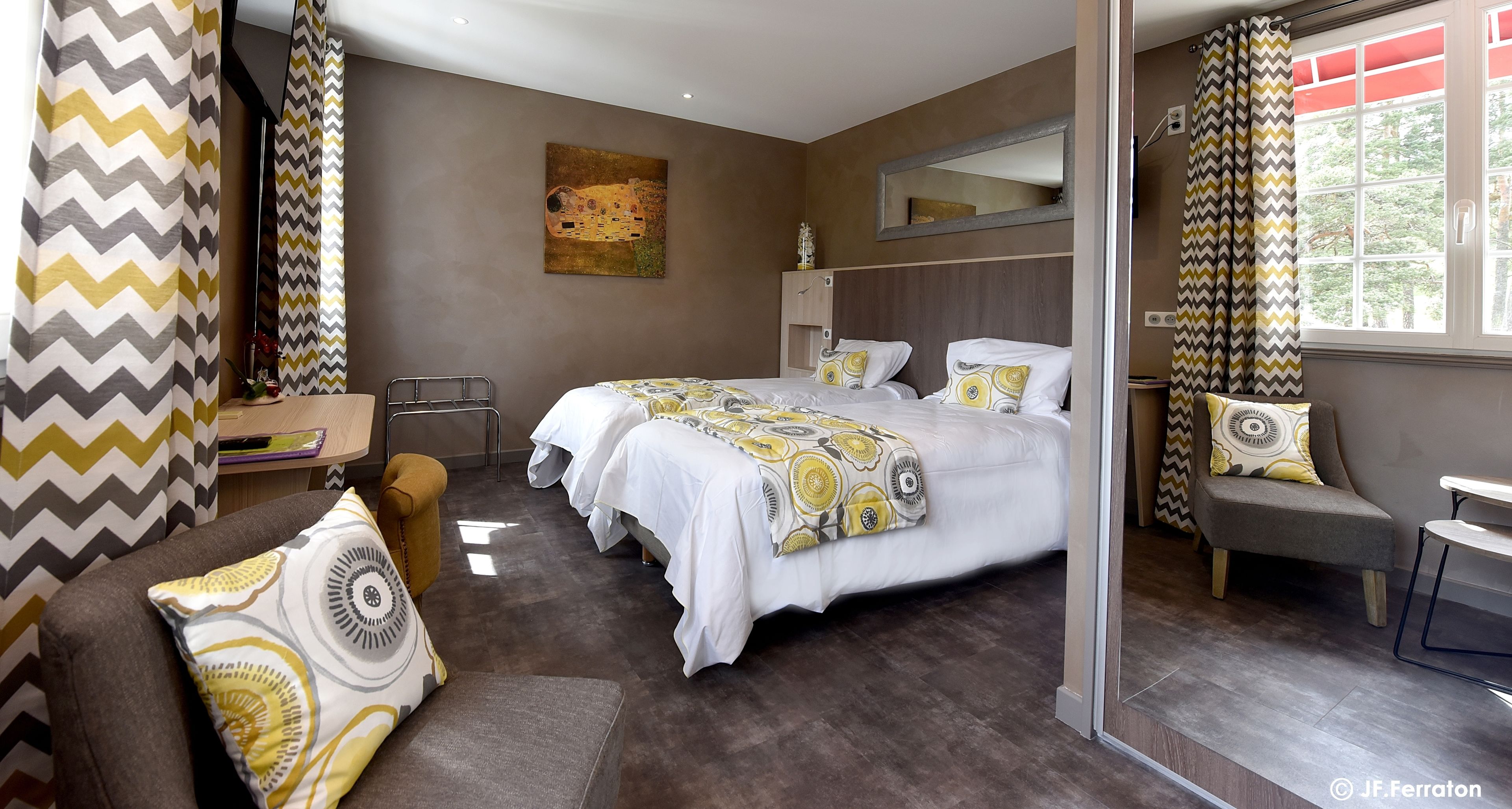 Une chambre d’hôtel moderne avec un grand lit, deux tables de chevet, un canapé et un miroir.