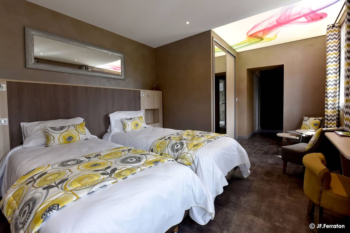 A hotel room with two beds, a large mirror, a desk, and a chair.