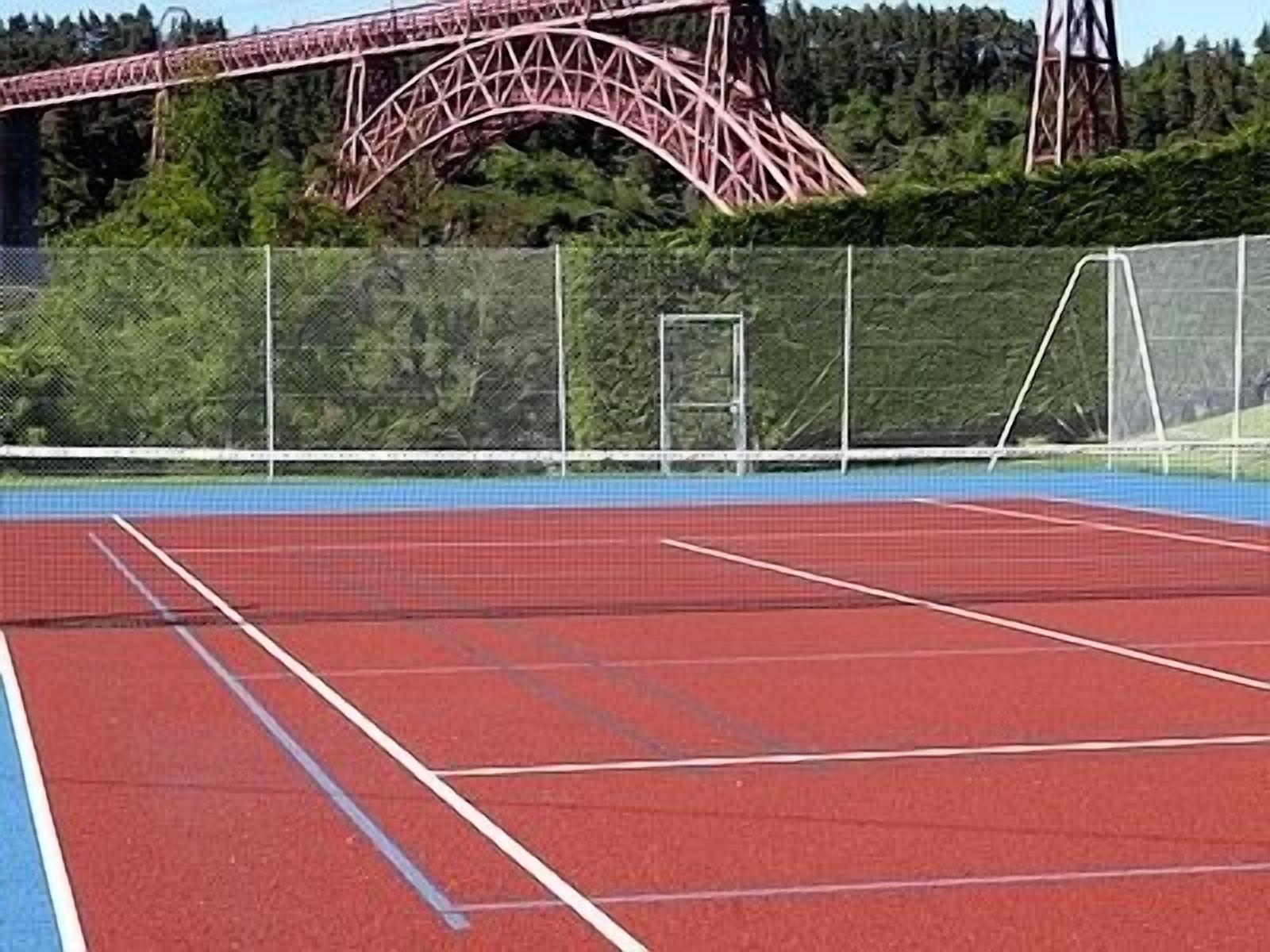 A tennis court with a red surface and white boundary lines.