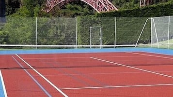 A tennis court with a red surface and white boundary lines.