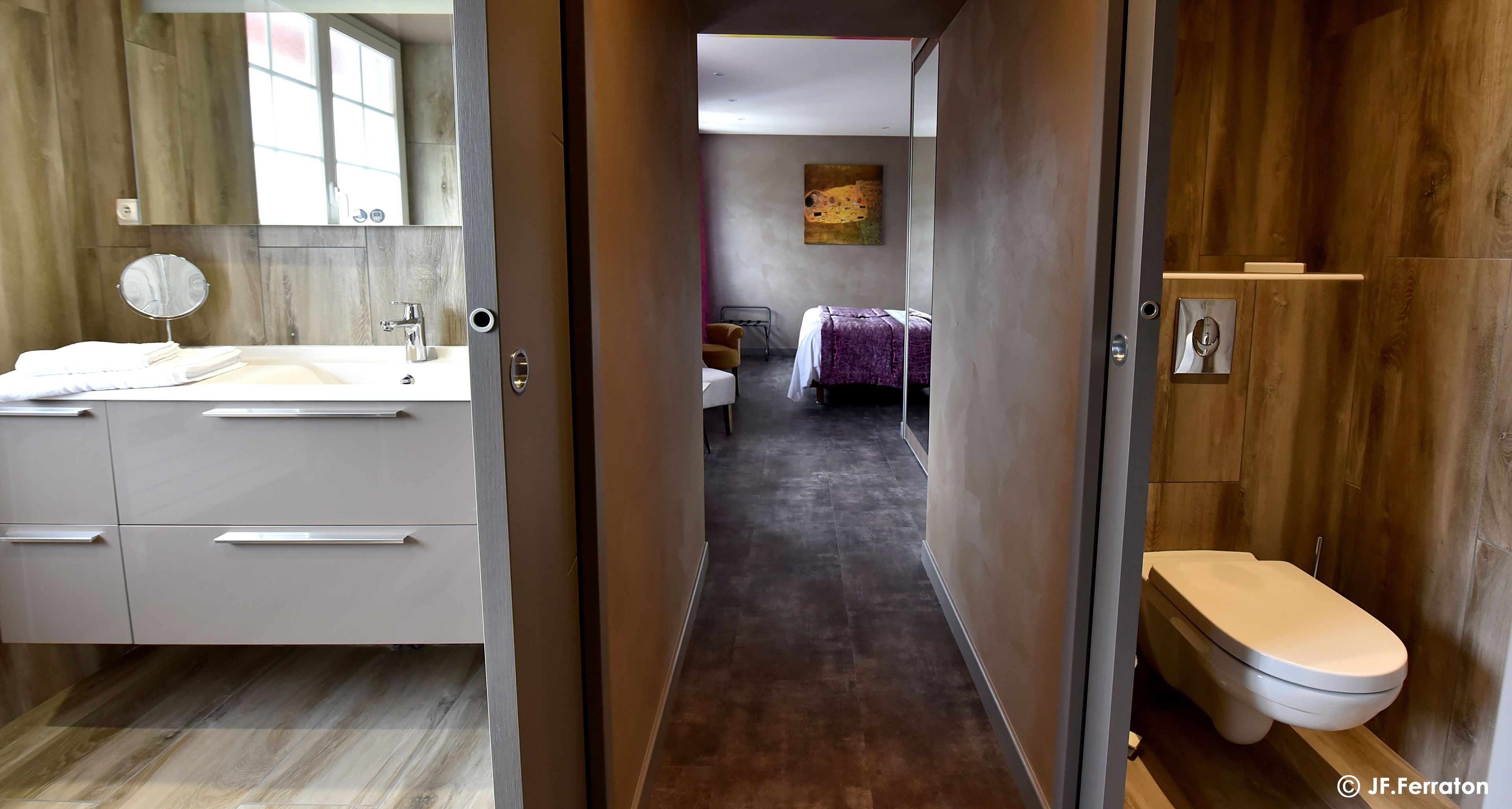 A modern bathroom with a wooden vanity, a toilet, and a mirror.