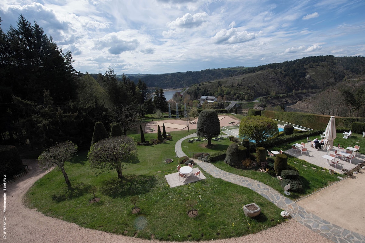 A landscaped garden with a patio area, stone pathway, and neatly trimmed hedges.