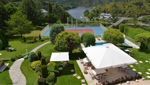 A tennis court, outdoor seating, and a scenic view of a lake and hills. - Hôtel Beau Site (Val-d'Arcomie)