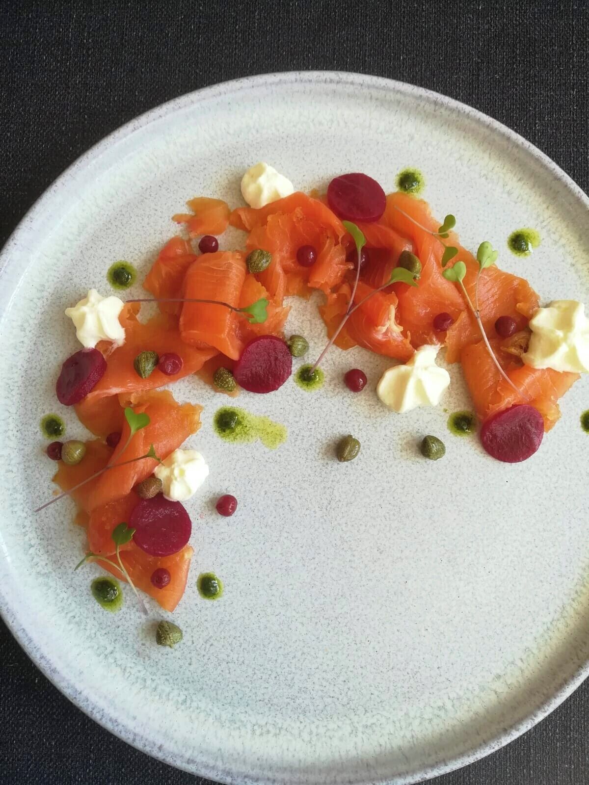 Une assiette de nourriture comprenant du saumon, de la crème et diverses garnitures.