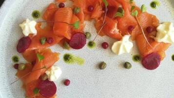 Une assiette de nourriture comprenant du saumon, de la crème et diverses garnitures.