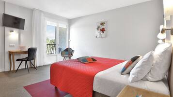 A hotel room with a bed, a desk, a chair, a TV, and a balcony.
