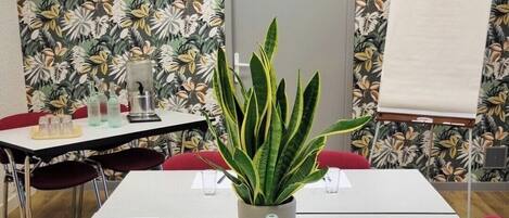 Un salón de conferencias con una pizarra, una planta en maceta y una mesa lista para una reunión.