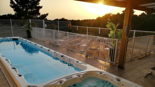 Een zwembad met een jacuzzi en een omheind terras.
