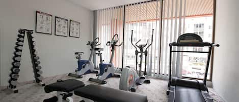 Un gimnasio con cintas de correr, elípticas y pesas libres.