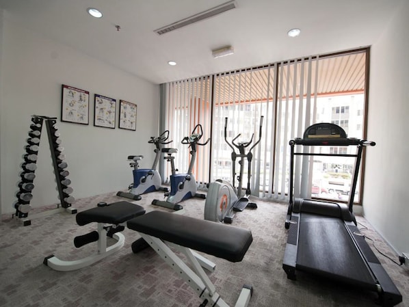 Une salle de sport équipée de tapis de course, de vélos elliptiques et de poids libres.