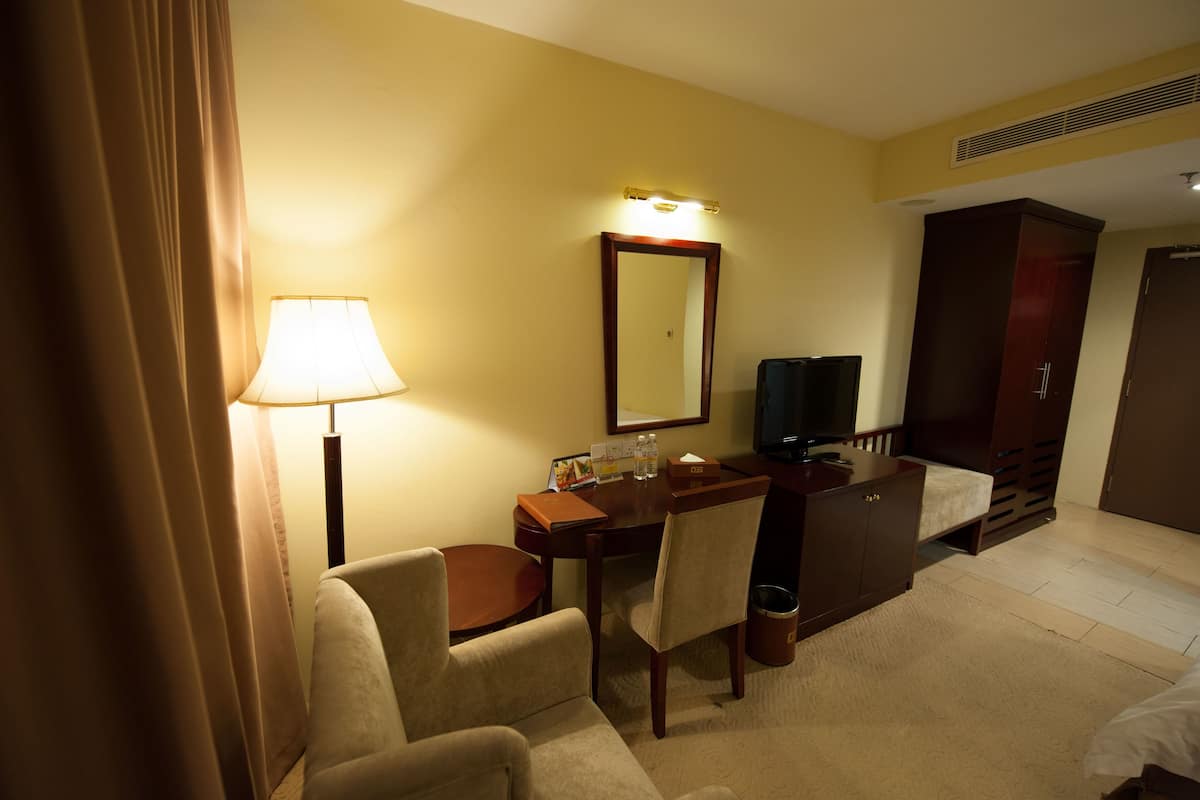 Habitació d'hotel amb escriptori, cadira, llit i televisió.