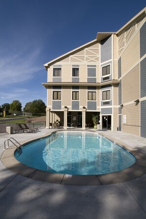 Un edificio de varios pisos con piscina, mobiliario exterior y un patio cubierto.