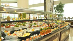 A buffet with various food items and a large plant in the background.