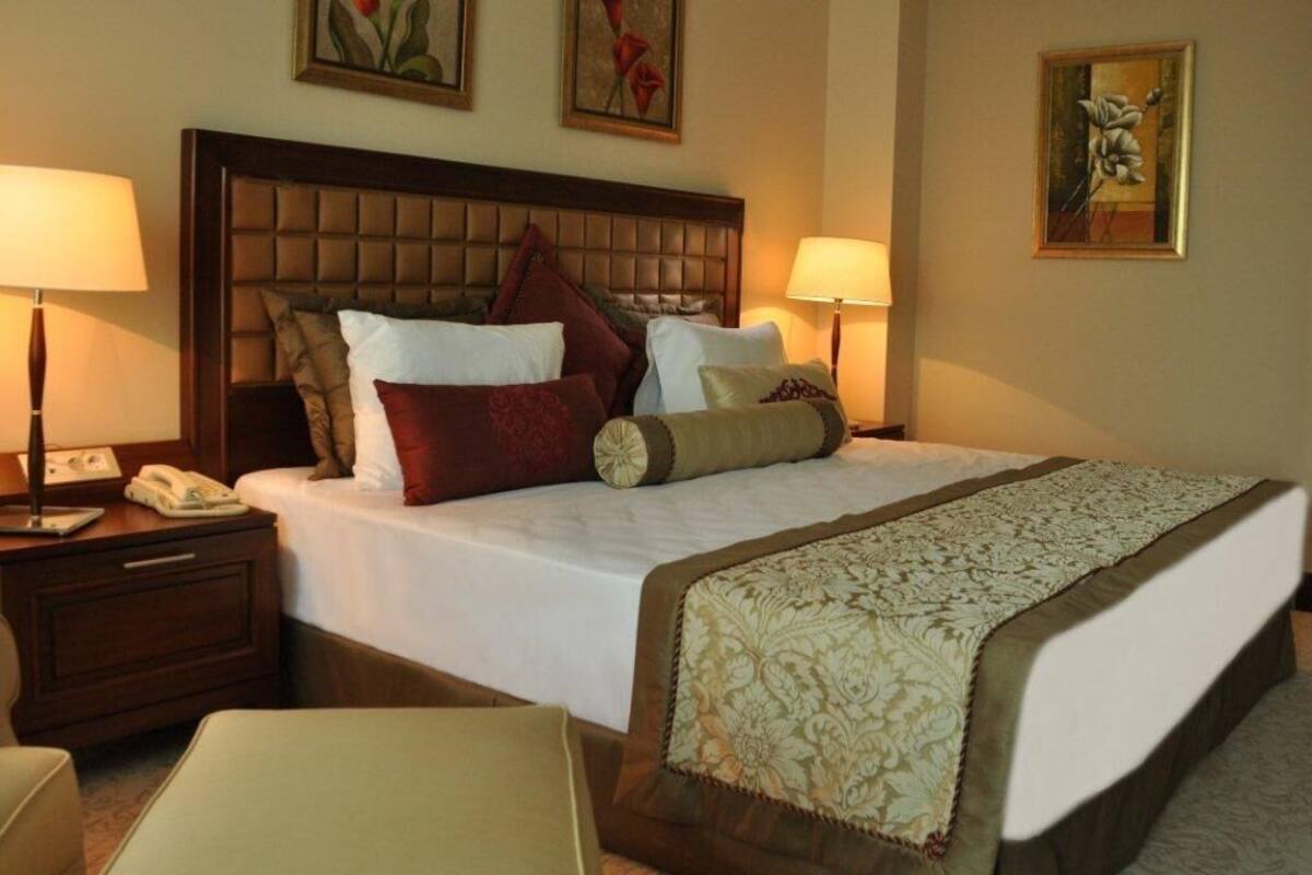 A hotel room with a large bed, two bedside tables, a telephone, and artwork on the walls.