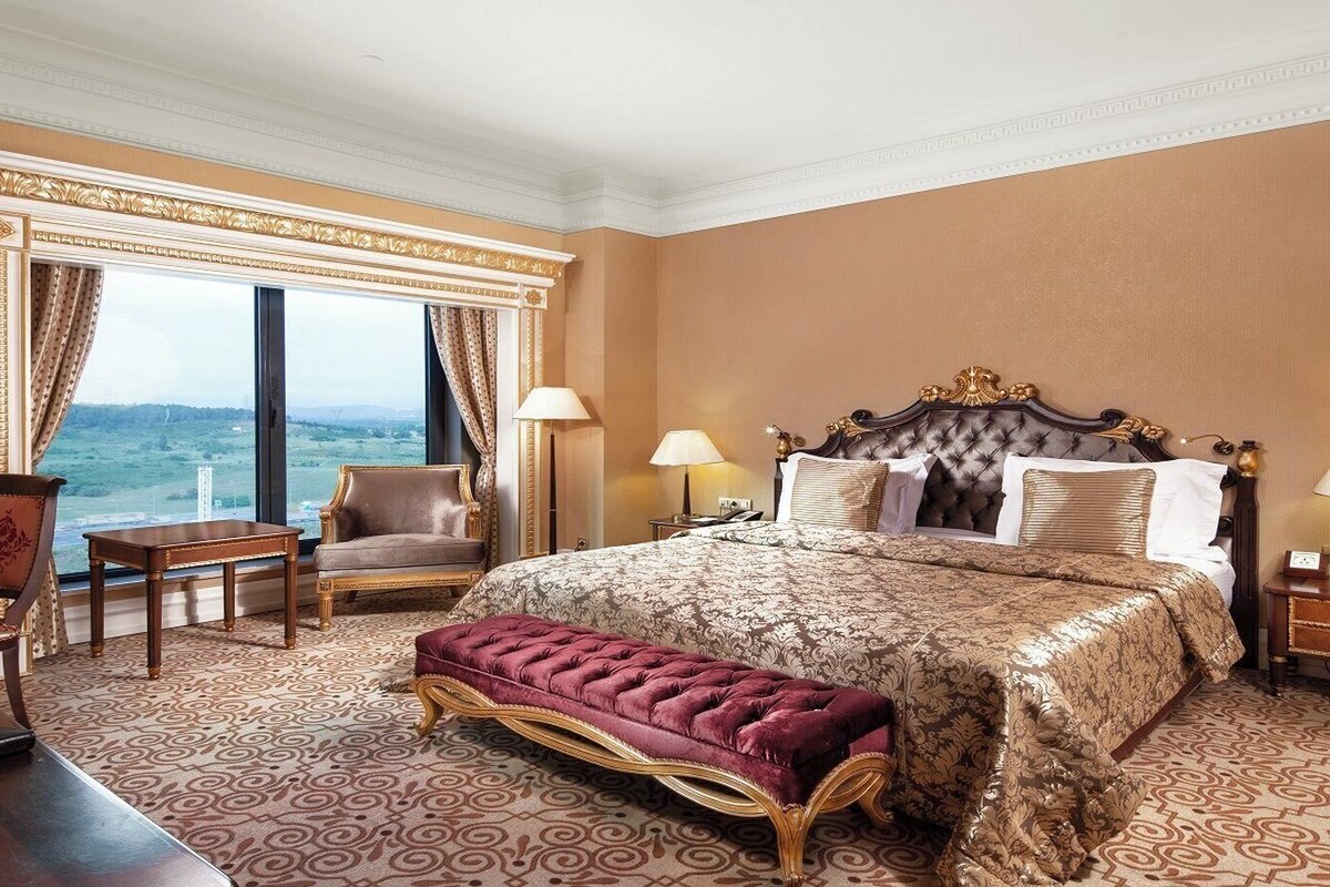 Een hotelkamer met een groot bed, een bureau, een stoel en uitzicht op de omgeving.