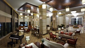 A spacious lobby with multiple seating areas, a grand piano, and elegant lighting fixtures.