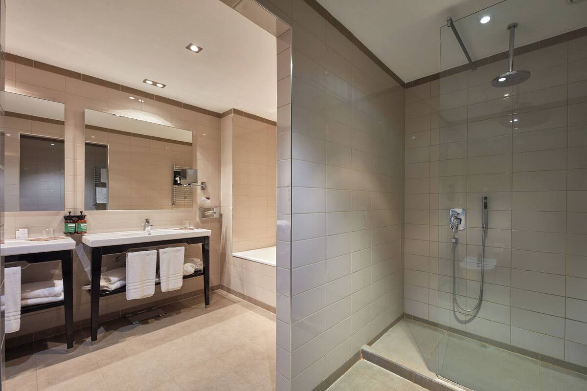Een moderne badkamer met een wastafel met dubbele wastafel, een grote spiegel en een douchecabine met glazen wanden.