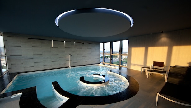 Una piscina interior moderna con diseño circular, amplias ventanas y un interior minimalista.