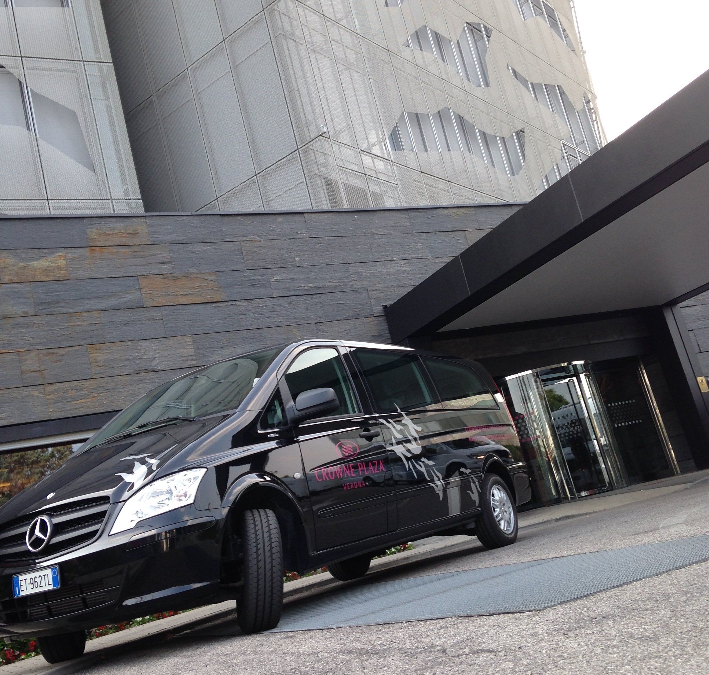Un SUV Mercedes-Benz Classe C noir est garé devant un bâtiment moderne doté d’une entrée en verre.