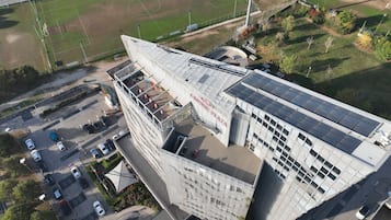 Un edificio moderno con un diseño angular distintivo, que cuenta con un jardín en la azotea y paneles solares.