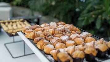 A buffet table with a variety of pastries, including croissants and muffins, arranged neatly.
