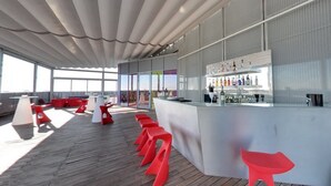 A modern bar area with a bar counter, red stools, and a glass display of bottles.