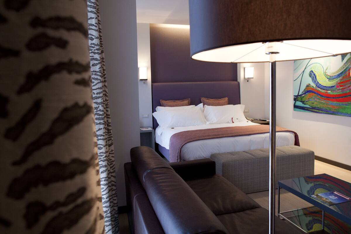Een moderne hotelkamer met een groot bed, een bank, een kleine tafel en een lamp.