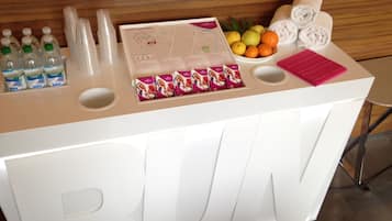 Un comptoir d’accueil avec des bouteilles d’eau, une carte, des fruits et des serviettes.