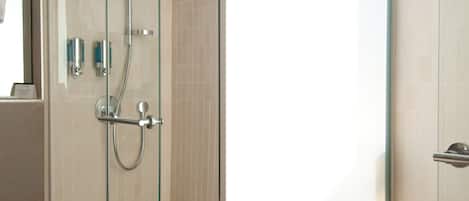 A modern bathroom with a glass-enclosed shower, a large sink with a mirror, and a towel rack.
