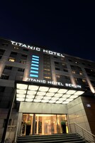 The exterior of the Titanic Hotel Berlin, featuring a prominent illuminated sign and a modern facade.