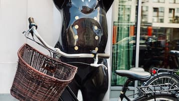 A bicycle with a wicker basket and a bear statue with raised arms.