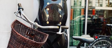 Una bicicleta con una cesta de mimbre y una estatua de oso con los brazos levantados.