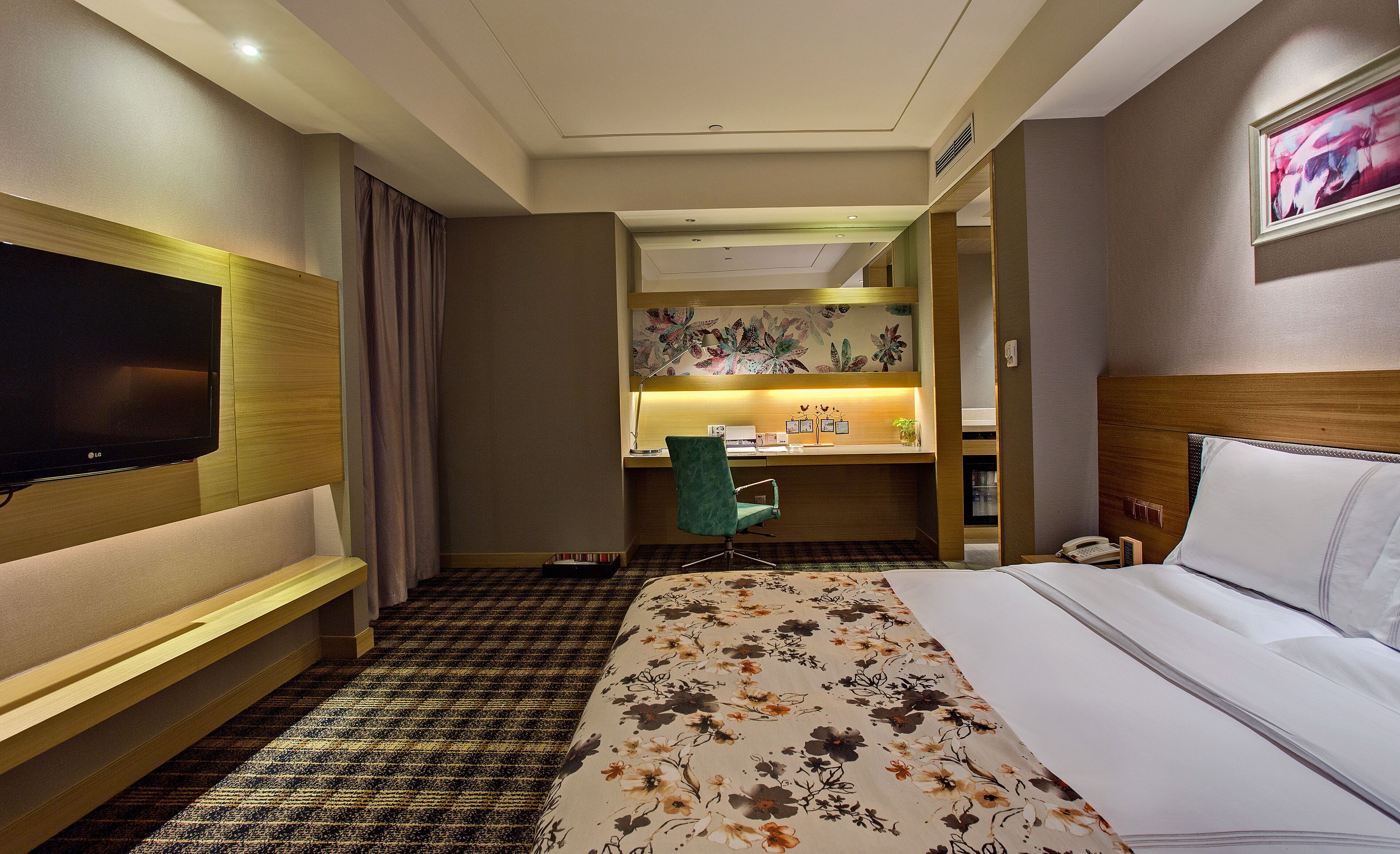 Habitación de hotel con cama, escritorio, silla, televisión y baño visible a través de una puerta abierta.