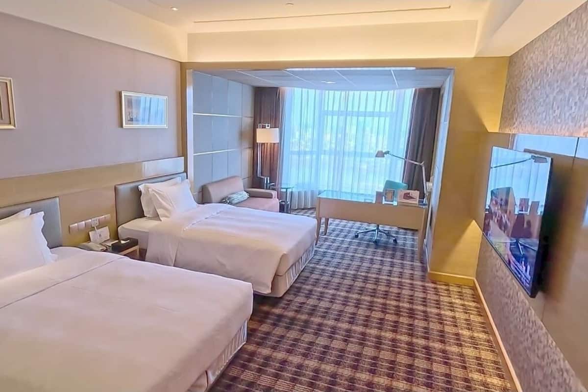 Une chambre d’hôtel avec deux lits, un bureau, une chaise et un téléviseur.