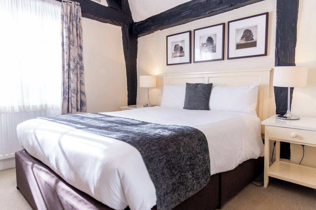 A hotel room with a large bed, two bedside tables, a headboard, and three framed pictures on the wall.