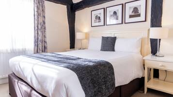 Habitación de hotel con una cama grande, dos mesitas de noche, un cabecero y tres cuadros enmarcados en la pared.