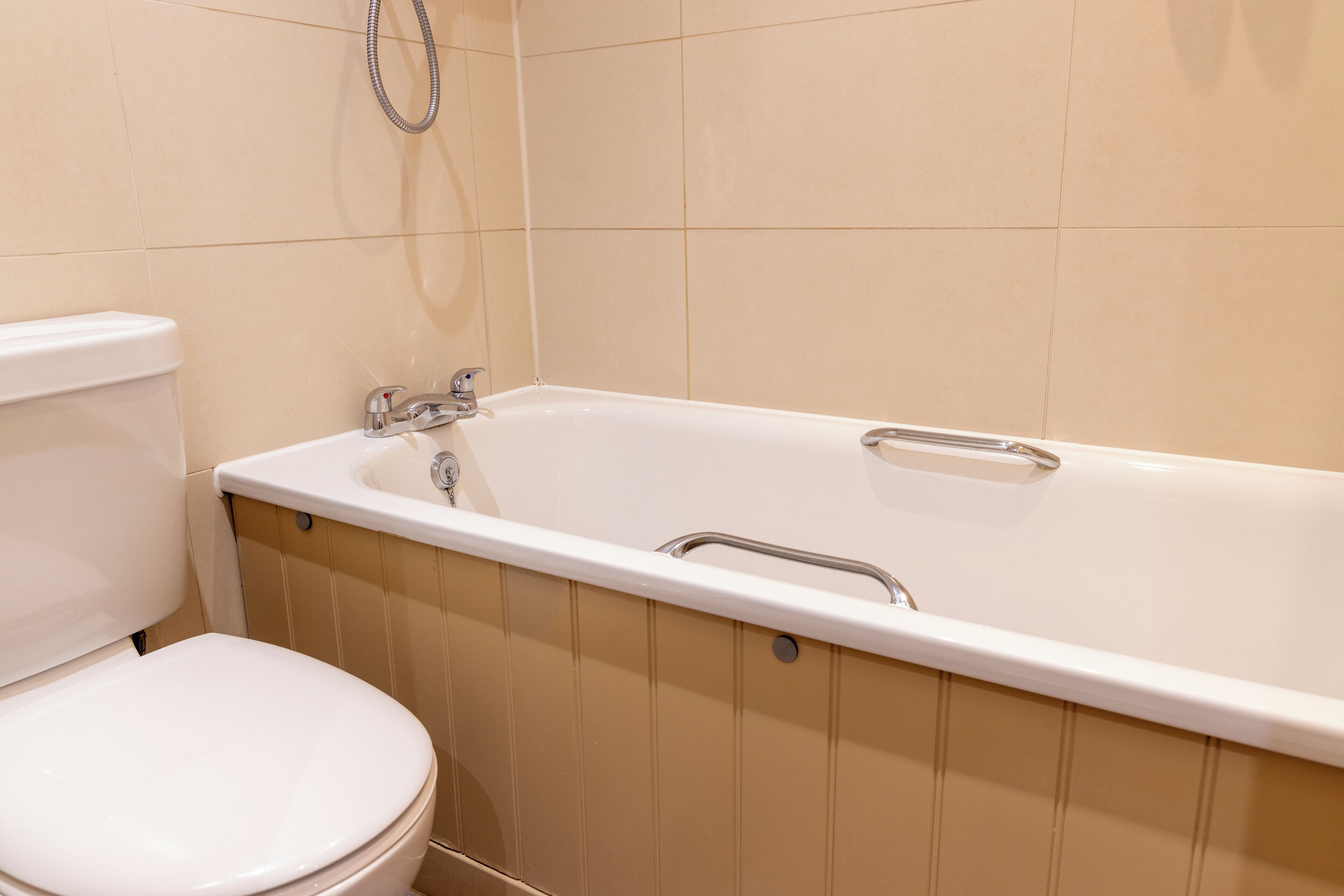 A bathroom with a toilet, a bathtub, and a showerhead.