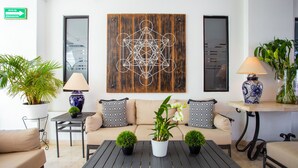 A modern lounge area with a sofa, coffee table, potted plants, and decorative items. - Hotel Suites Mar Elena (Puerto Vallarta)