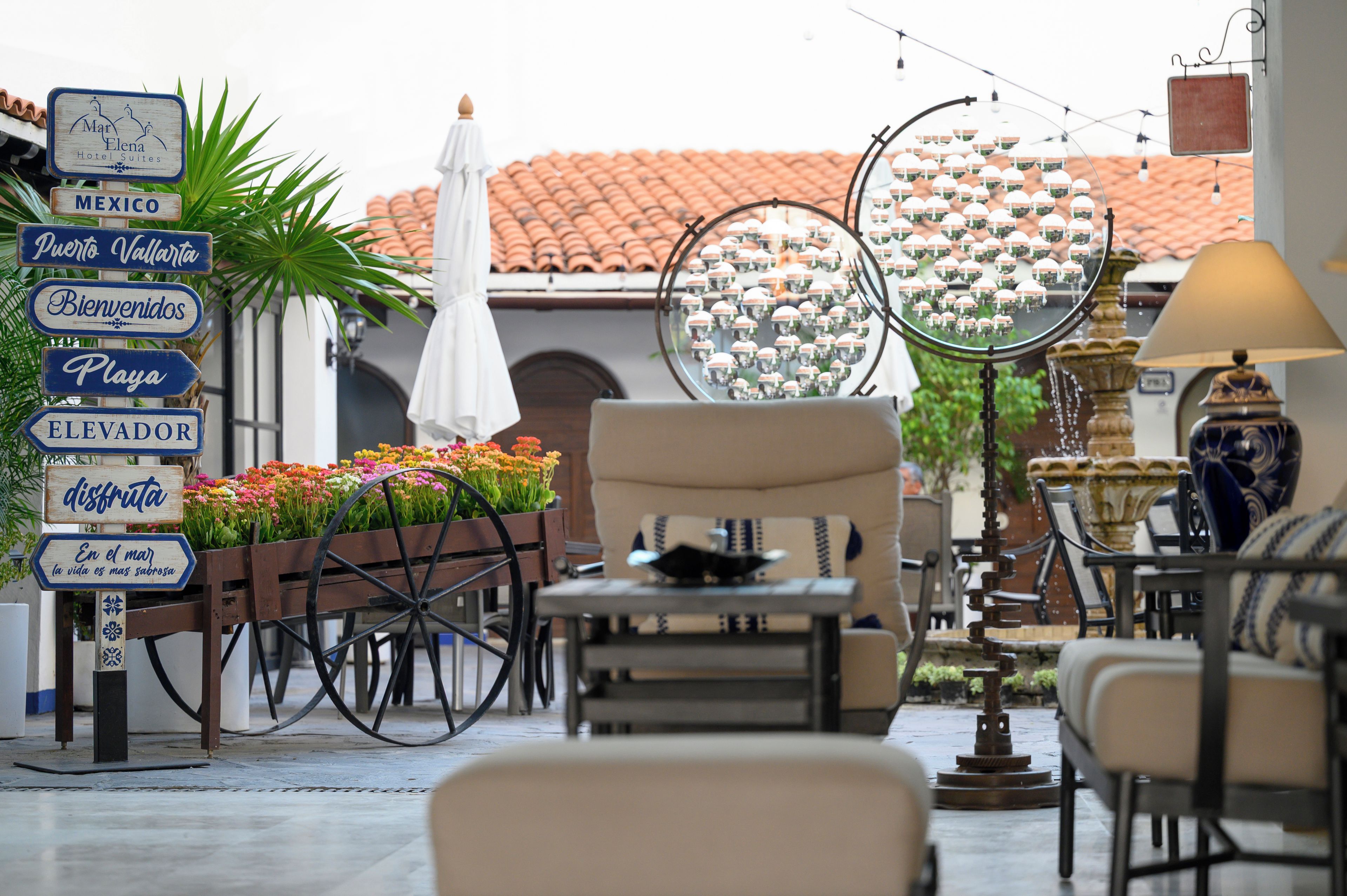 A patio area with outdoor seating, a signpost with directional signs, and a decorative mirror.