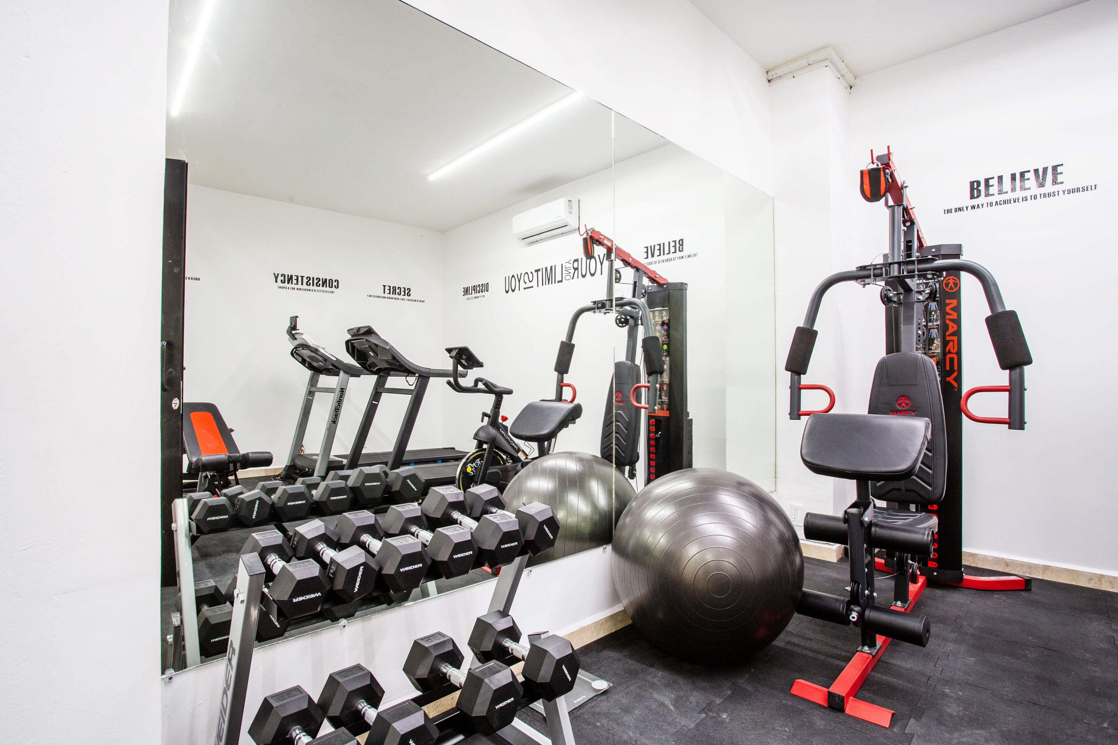 A gym with various exercise equipment, including dumbbells, treadmills, and exercise balls.