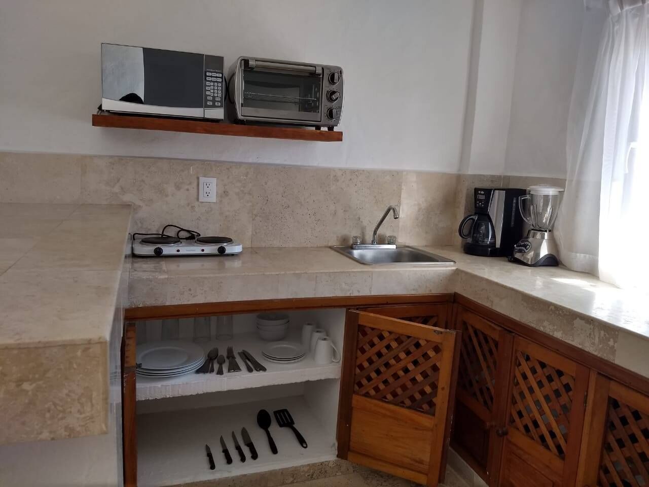 A compact kitchen with a microwave, toaster, and coffee maker on the countertop.