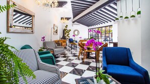 A modern living room with a checkered floor, a blue armchair, a houndstooth sofa, and a chandelier. - Hotel Suites Mar Elena (Puerto Vallarta)