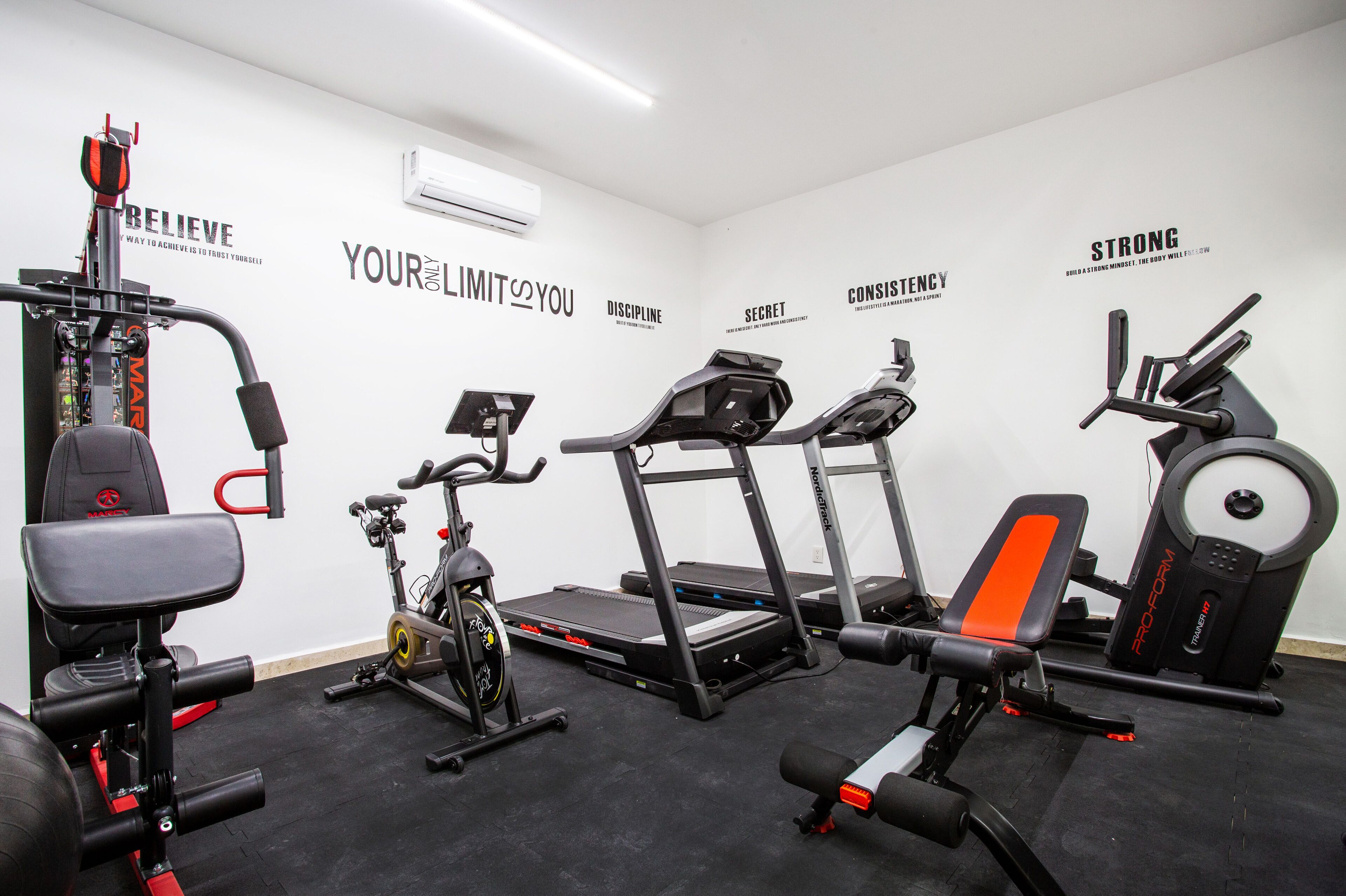 A gym with various exercise equipment including a treadmill, stationary bike, and weight machines.