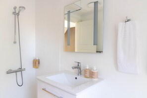 Ein Badezimmer mit einem weißen Waschbecken, einem Spiegel und einem Handtuchhalter.