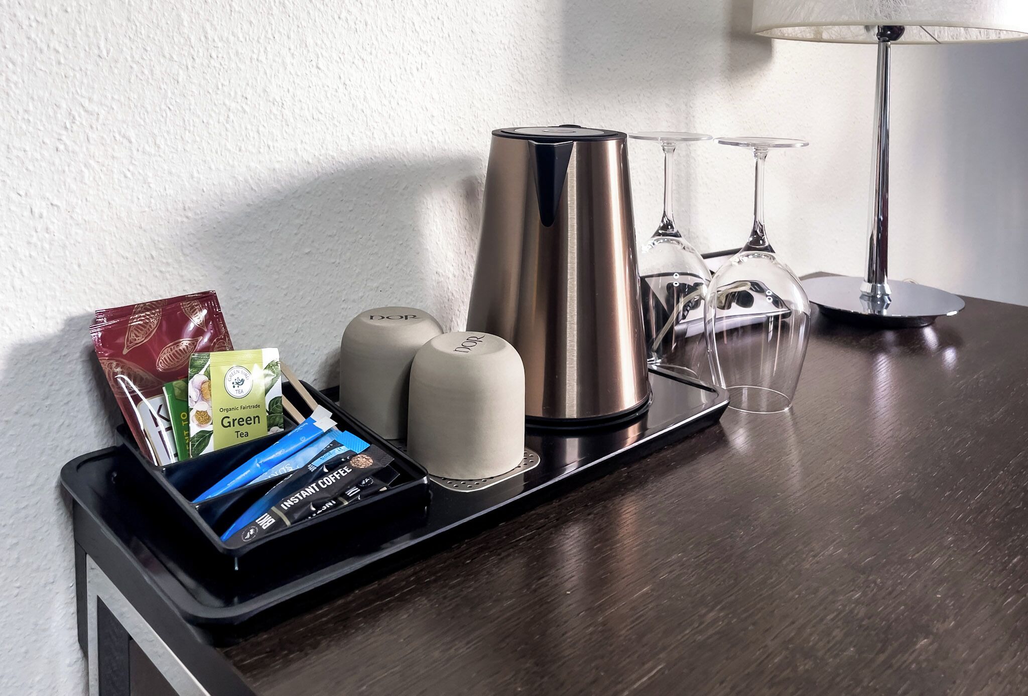 Una cafetera, bolsitas de té y vasos sobre una bandeja.