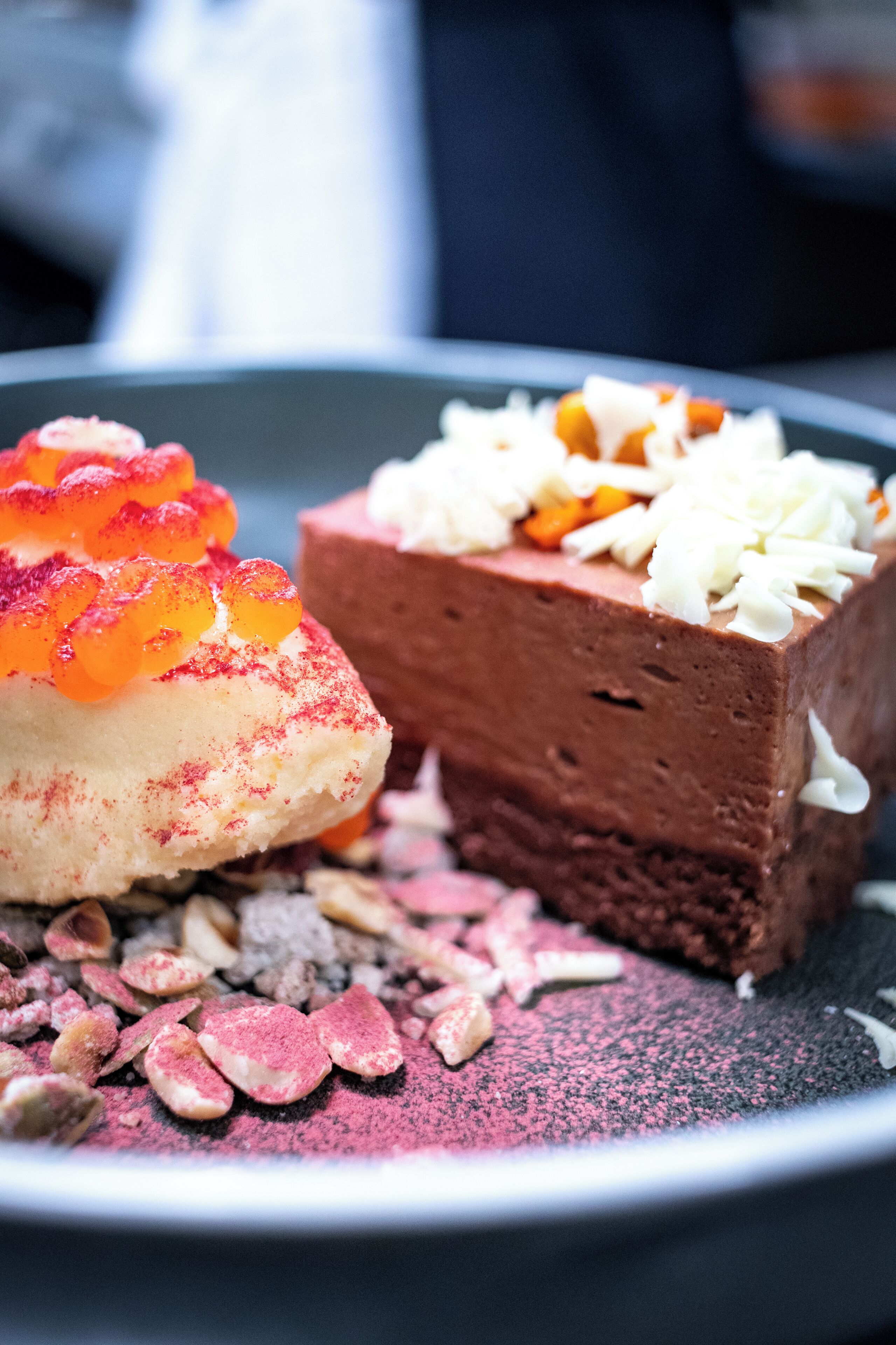 A dessert plate with two different types of desserts, one topped with orange and white elements, and the other with white and orange elements.