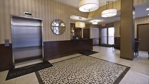 Un hall d’hôtel avec un comptoir d’accueil, une horloge et un tapis à motifs.